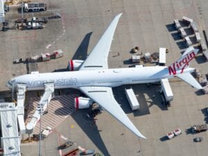 Virgin Australia Boeing 777-300ER parked at an airport gate with services