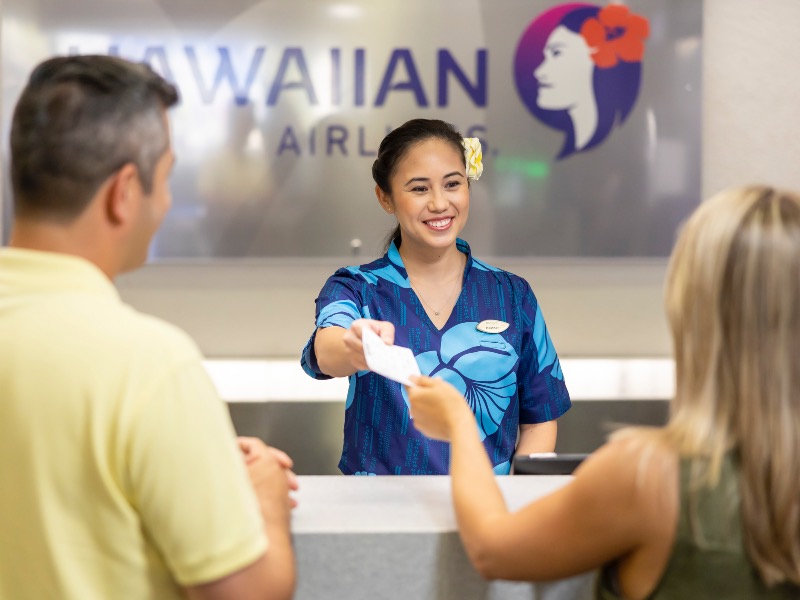 Hawaiian Airlines customer service agent hands over a boarding pass