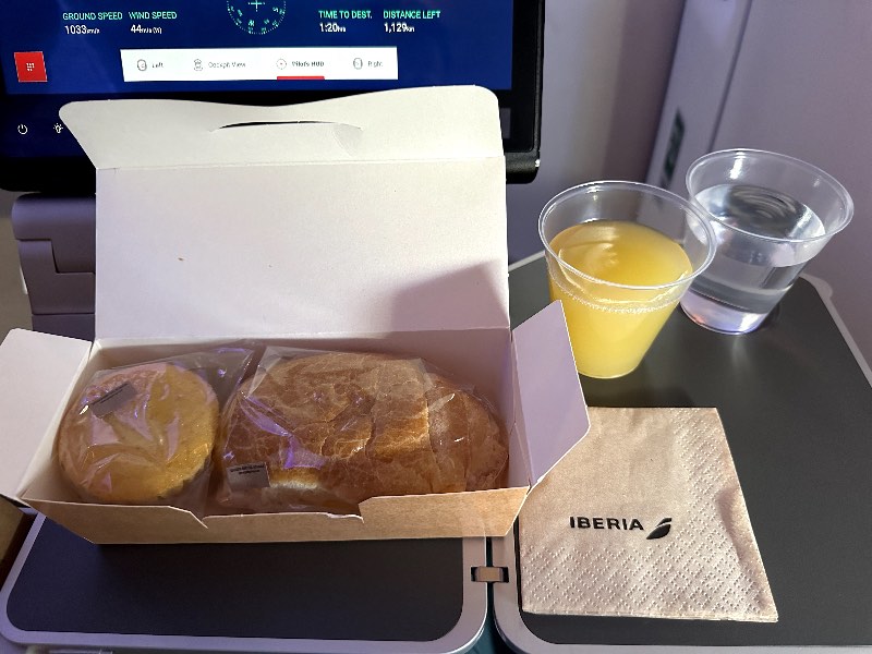 A ham and cheese croissant served with a muffin for breakfast in Iberia Premium Economy