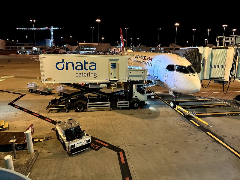 QantasLink A220 with a dnata catering truck at Melbourne Airport