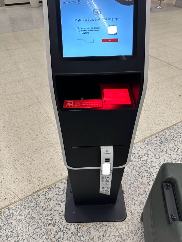 Qantas check-in kiosk printing a luggage bag tag