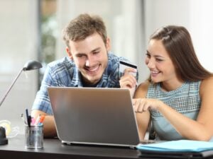 Couple comparing products buying on line with a laptop with a credit card