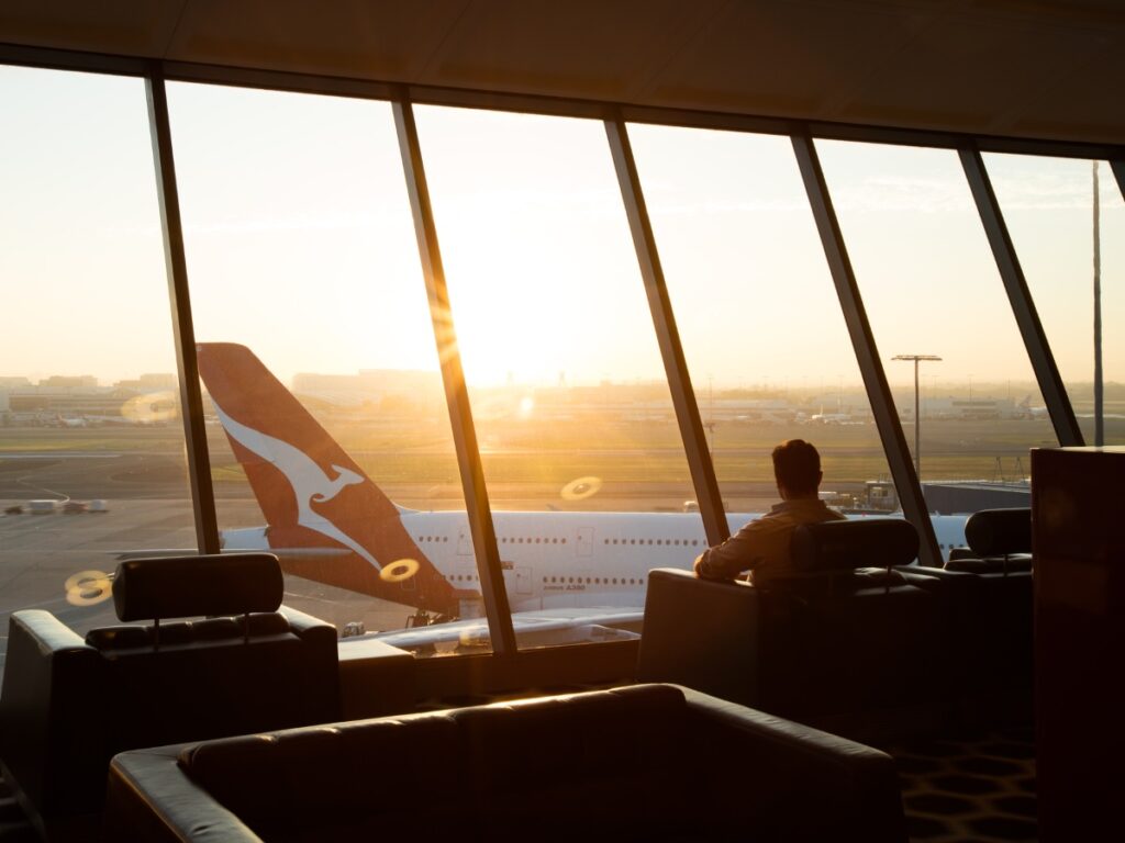 Man sitting in the Qantas First Lounge in Sydney with an Airbus A380 in the background